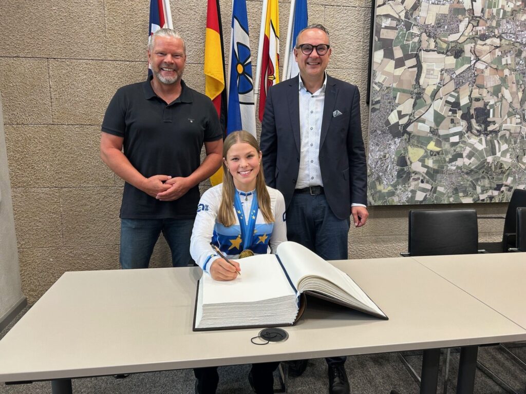 (stehend von links) Michael Lutter vom Stadtsportverband Lemgo und Bürgermeister Markus Baier freuten sich über die sportlichen Höchstleistungen von Europameisterin Antonia Blome (sitzend).