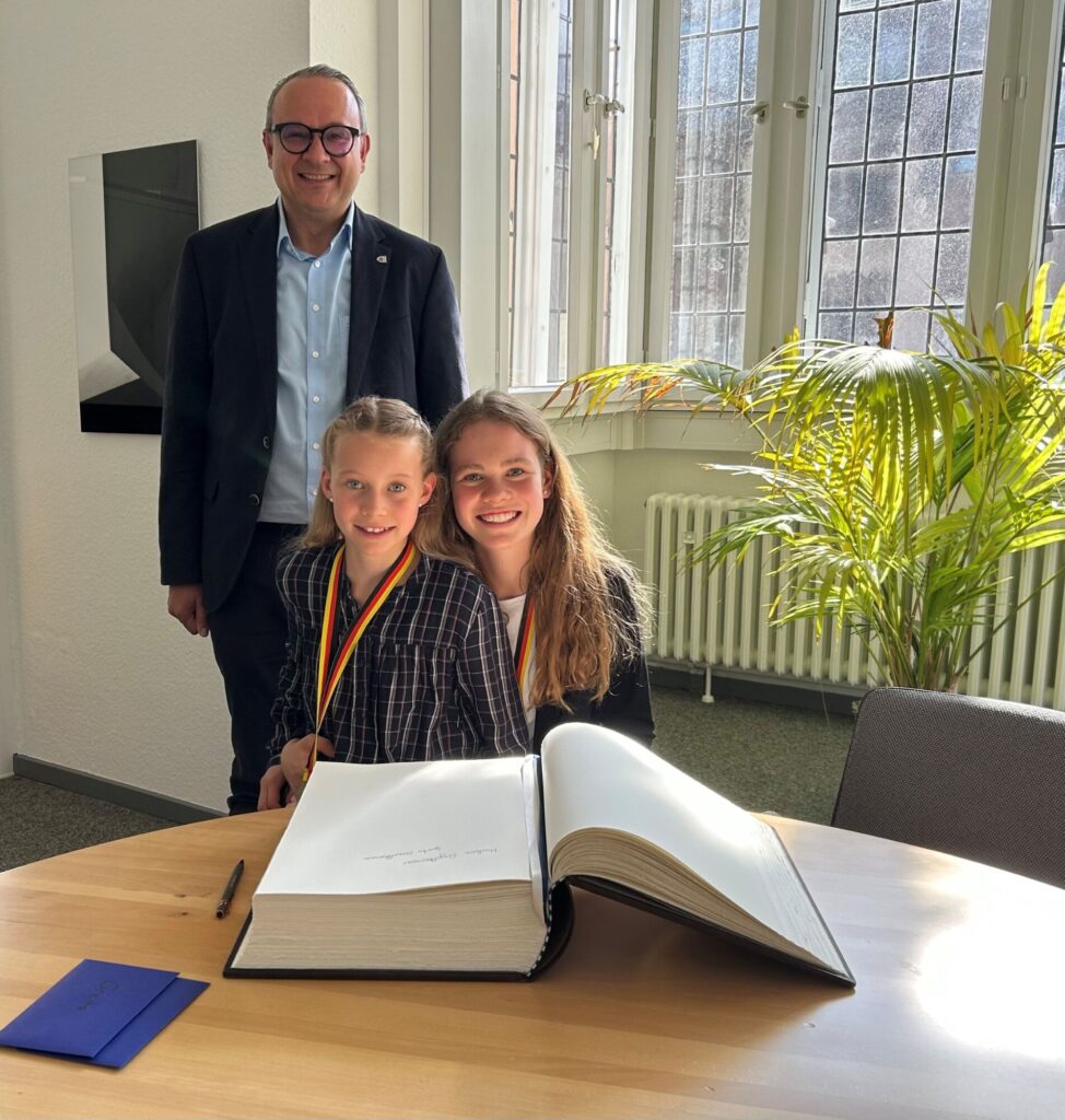 Bürgermeister Markus Baier (stehend) gratulierte den Schwestern (von links) Greta und Marlene Engelkemeier vom RSV "Tempo" Lieme herzlich zu ihrem Erfolg bei den Deutschen Meisterschaften.